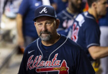 Braves Manager Announces a Slew of Injury Returns Man wearing a navy Atlanta Braves cap and jersey, looking at the camera at a game.