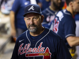 Man wearing a navy Atlanta Braves cap and jersey, looking at the camera at a game.