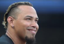 Braves World Series Champion Is Still In The Minor Leagues Close-up of a smiling man's face, ear with a silver hoop earring, short beard, and hair with blond tips against a dark background.