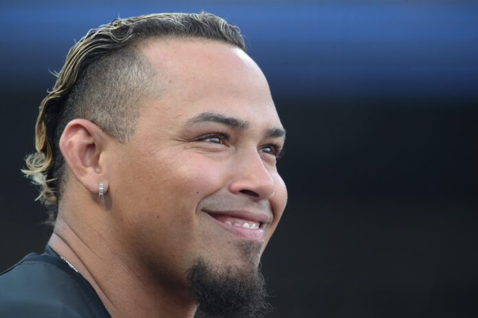 Braves World Series Champion Is Still In The Minor Leagues Close-up of a smiling man's face, ear with a silver hoop earring, short beard, and hair with blond tips against a dark background.