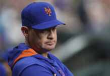 New York Mets Fire Head Coach Effective Immediately Close-up of a man wearing a blue cap with an orange Mets logo, looking to the right.