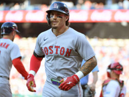 Boston Red Sox player wearing helmet and gray uniform with black face paint, on the field during a game.