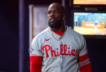 Phillies Outfield Left With Huge Void After Latest Injury Portrait of a Black man wearing a Philadelphia Phillies baseball jersey with a silver chain, indoors.