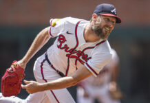 Braves Rainout Gives The Team Some Much-Needed Rest Baseball pitcher in Braves uniform mid-throw with a red glove extended