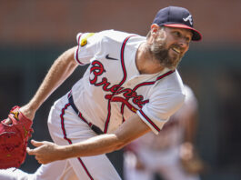 Baseball pitcher in Braves uniform mid-throw with a red glove extended