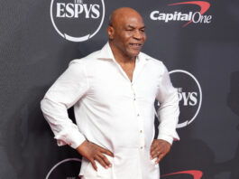Man in a white button-down shirt posing with hands on hips at the ESPYS backdrop.
