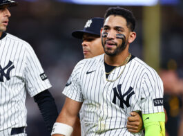 Baseball player in a Yankees pinstripe uniform with black face paint and a gold chain.