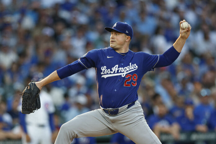 Dodgers pitcher in blue uniform throwing a pitch during a game with a blurred stadium crowd in the background